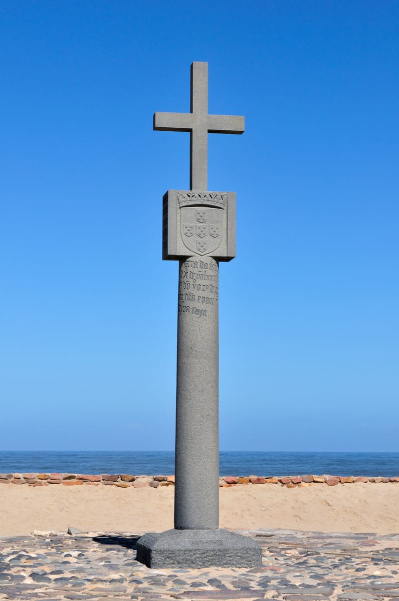 Nachbildung eines steinernen Kreuzes auf einem Sockel vor blauem Himmel