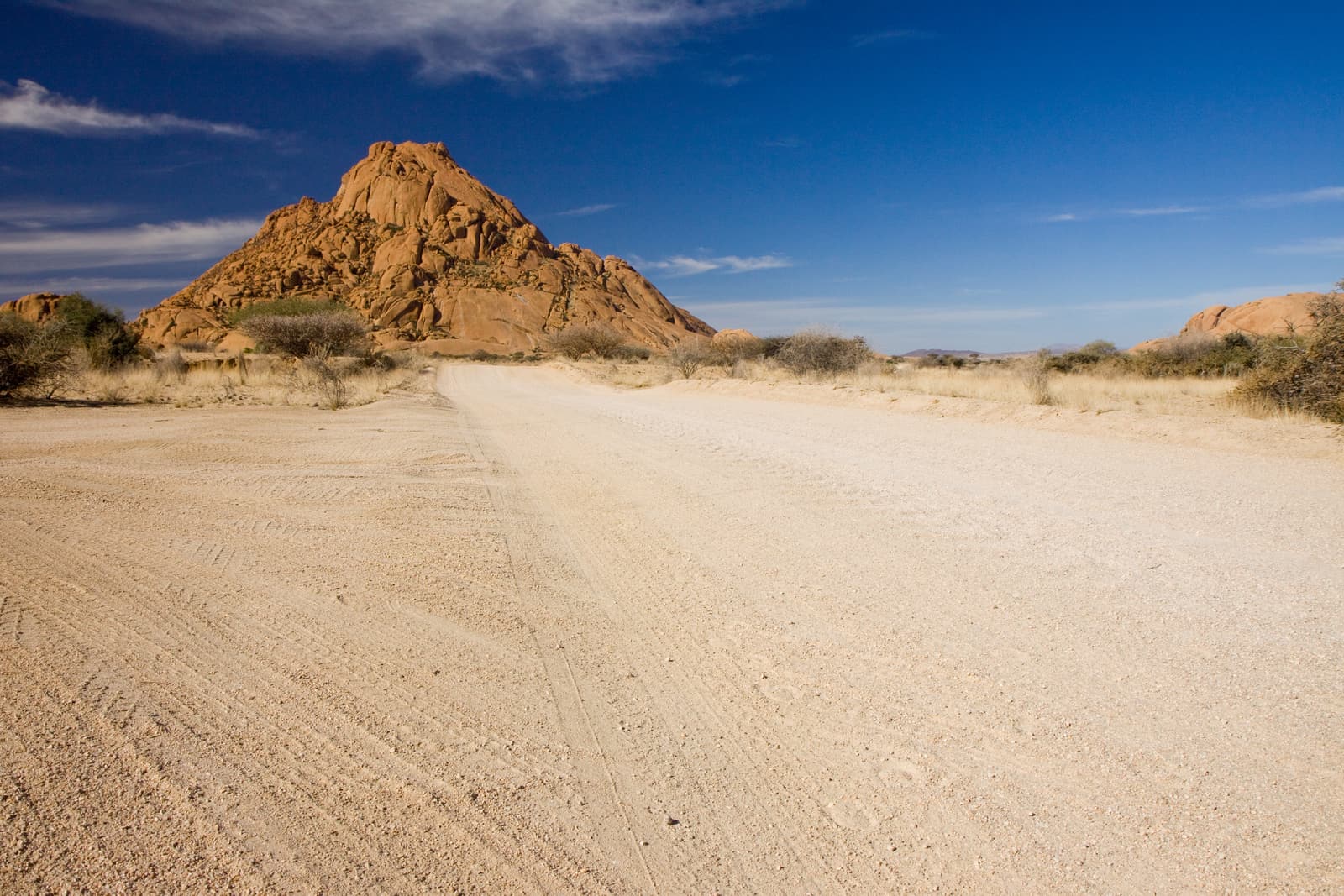 Schotterpiste, dahinter der Granitgipfel der Spitzkoppe