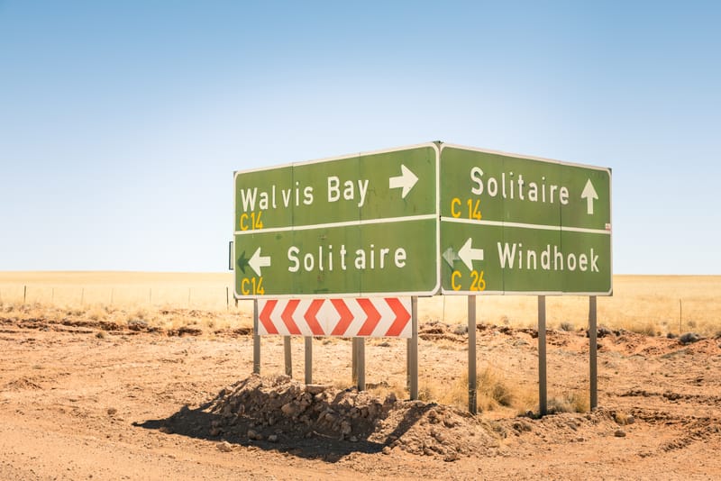 Wegweiser nach Walvis Bay, Solitaire und Windhoek an einer Schotterstraße